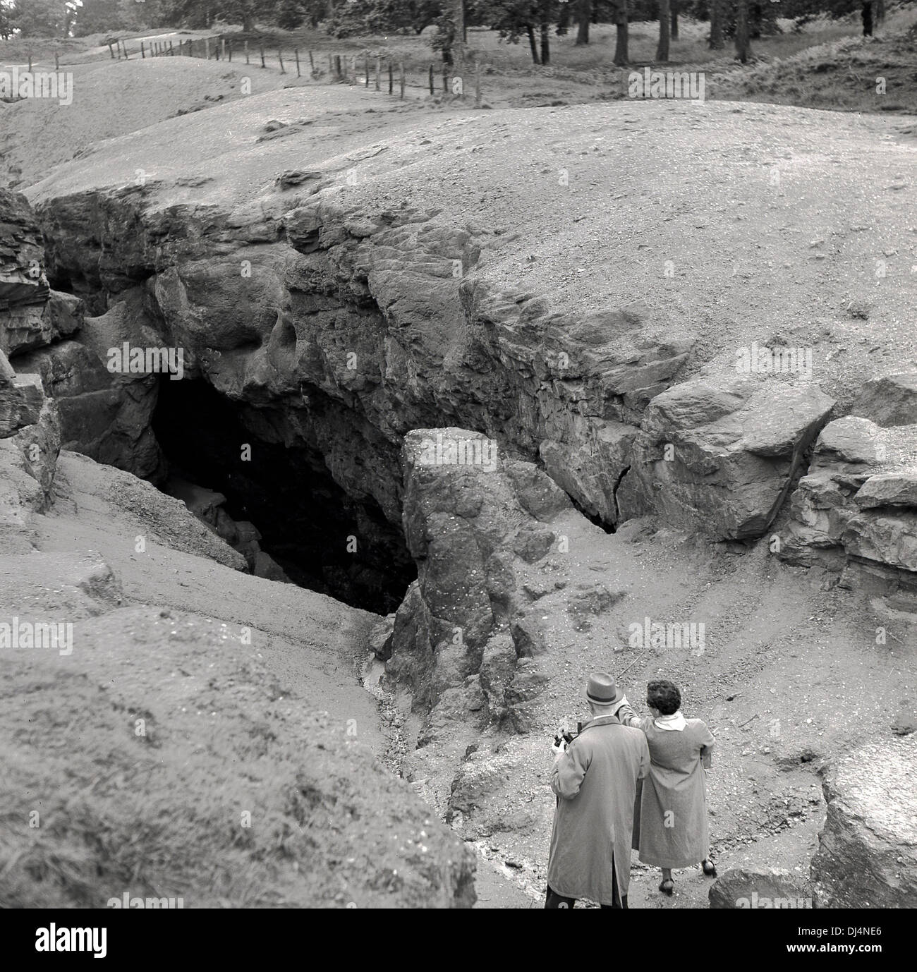1950s-historical-two-people-studyt-a-large-hole-or-cave-or-rocky-opening-DJ4NE6.jpg